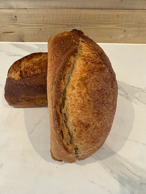 Emmerbrød med gyllenbrun skorpe og et langt snitt på toppen.