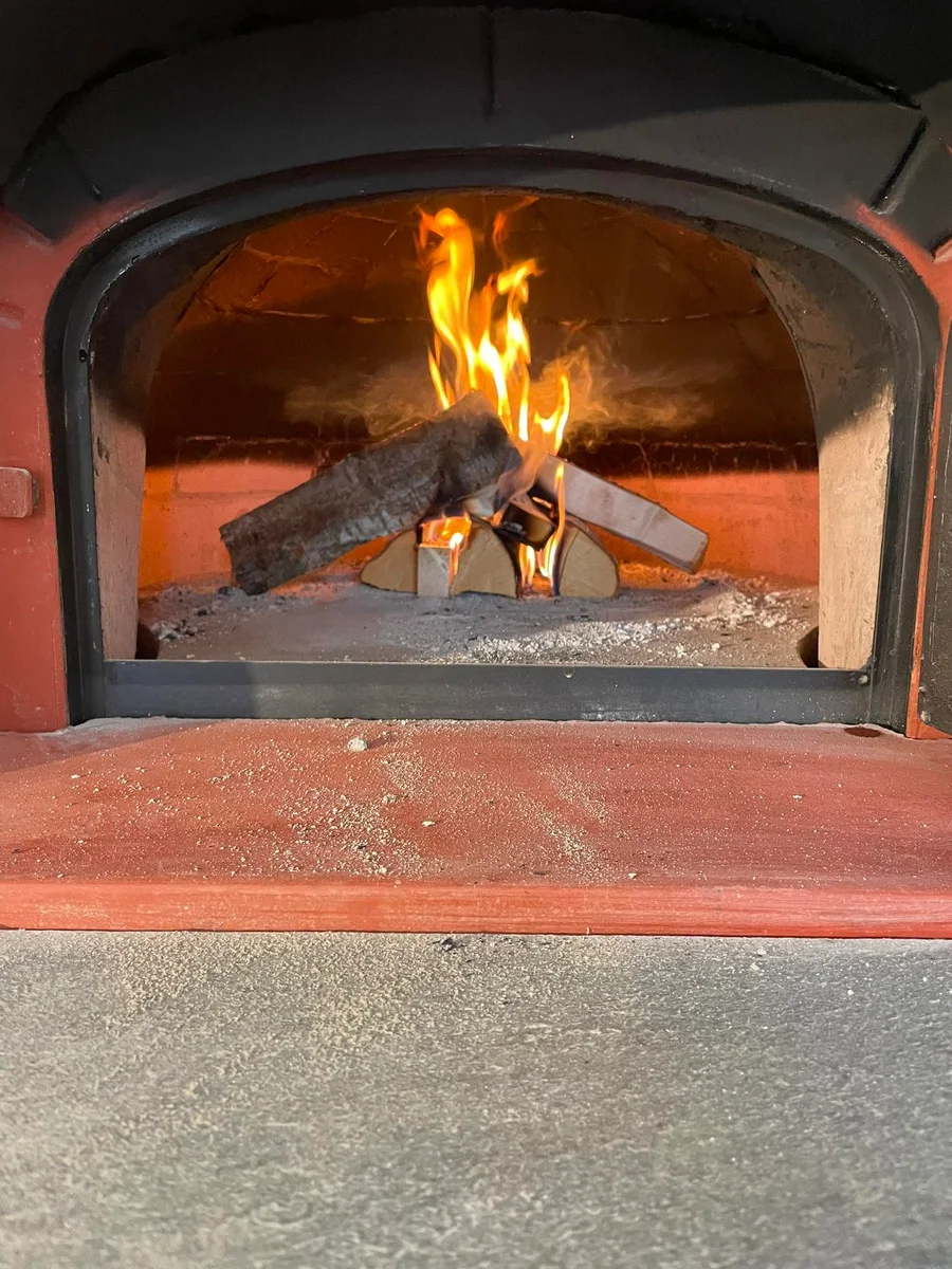 Ved og flammer inne i Hannes steinovn, sett gjennom den åpne ovnsdøren.